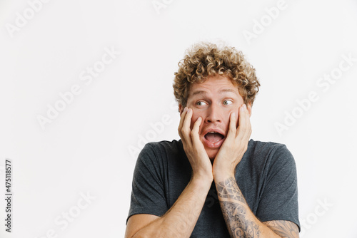 Young curly man expressing surprise and screaming at camera