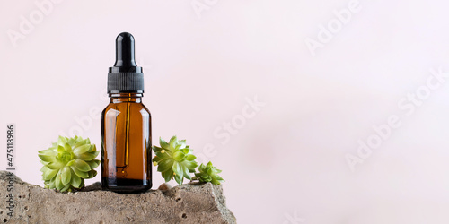 Fotografie Mock up serum for the skin of the face and body in a dark pipette surrounded by natural materials