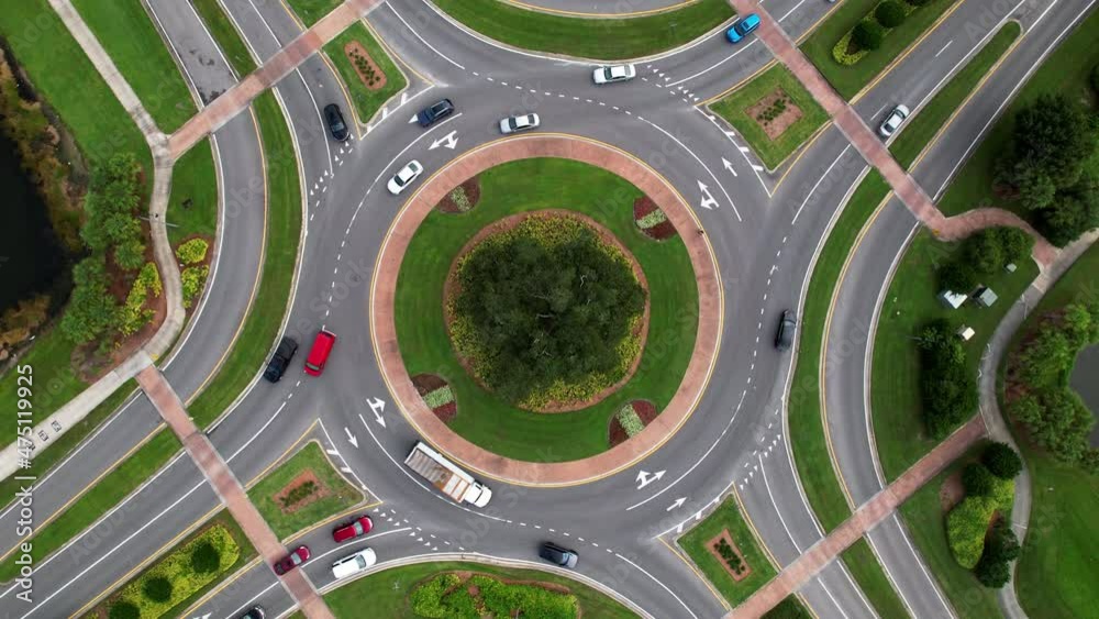 Aerial overhead shot of two lane traffic circle with cars and trucks going around.