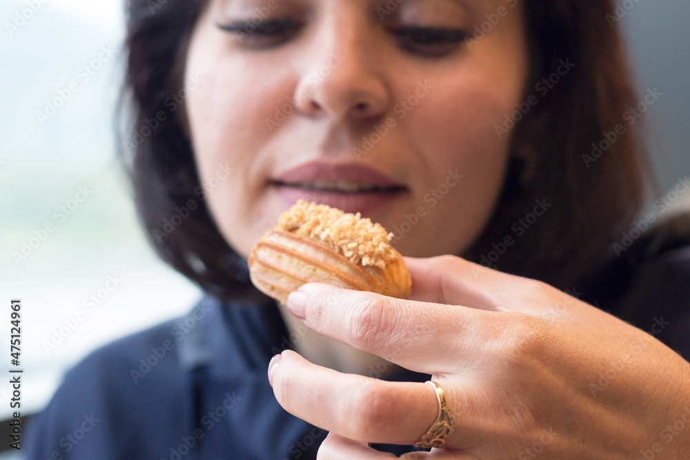 A beautiful adult woman cafe is happy to try a mini eclair cake. A beautiful adult woman cafe is happy to try a mini eclair cake.