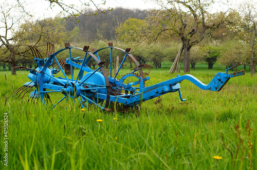 A historical hay tedder decorates a meadow orchard in Hesse, Germany. photo