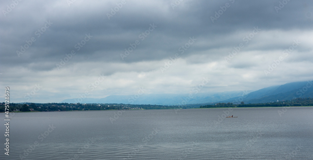 beautiful mountain landscape on a cloudy day with a person rowing in a lake - photography with negative space