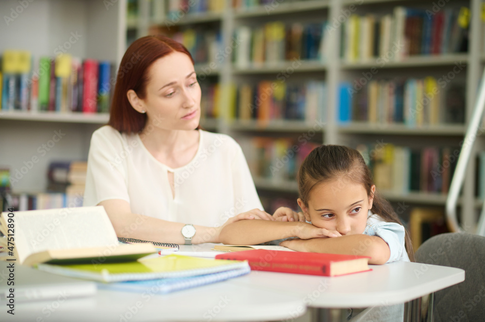 Caring woman touching hand of girl tired of studying Caring woman touching hand of girl tired of studying