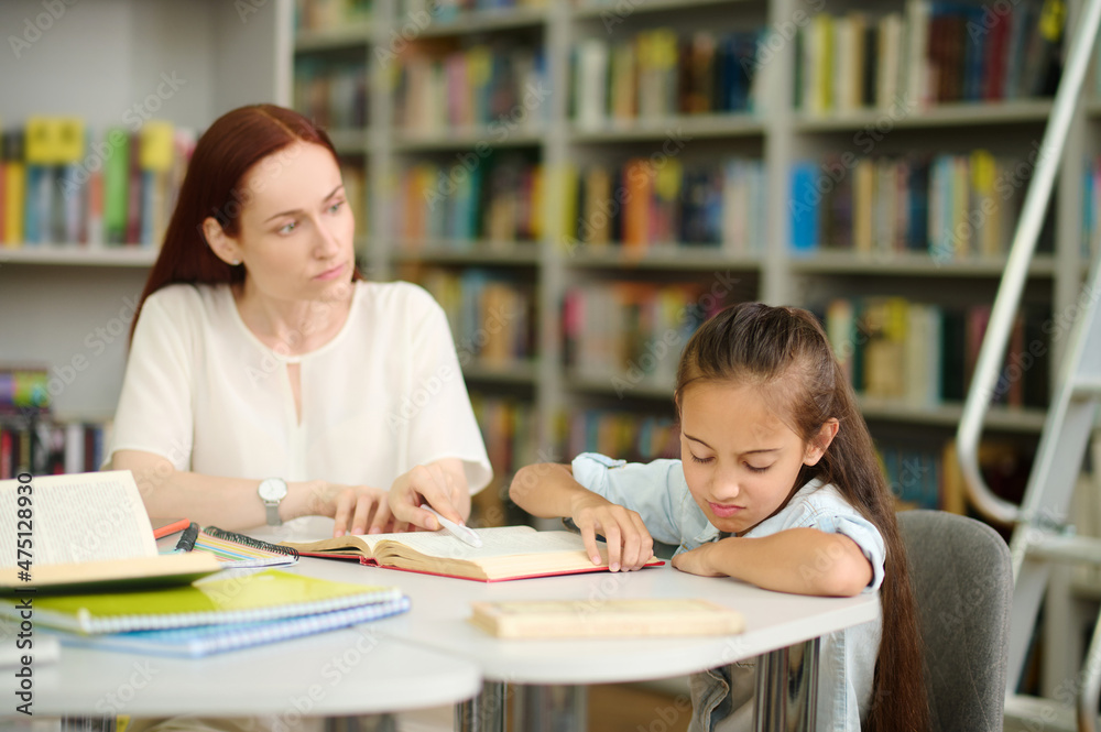 Woman looking at girl refusing to study Woman looking at girl refusing to study