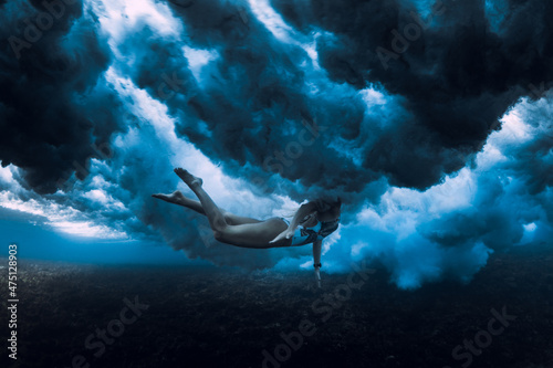 Woman swim under ocean wave. Duck dive under crashing wave