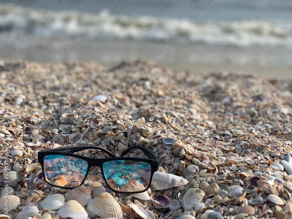 Summer vacation beach background. Sunglasses in shell sand. Sunglasses on the beach. Vacation concept. Summer vacation beach background. Sunglasses in shell sand. Sunglasses on the beach. Vacation concept.