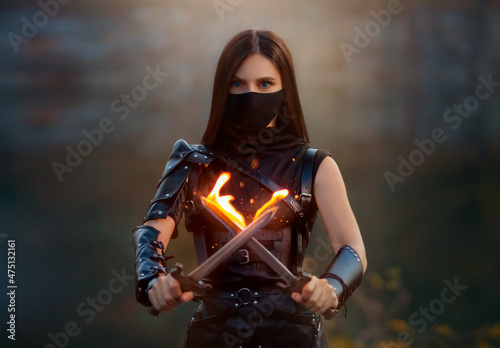 Photo Fantasy fighting woman assassin holds in hands burning daggers