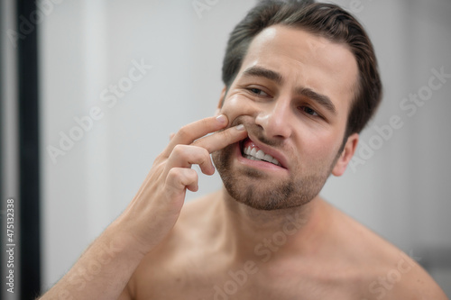 Man checking his teeth and looking disturbed