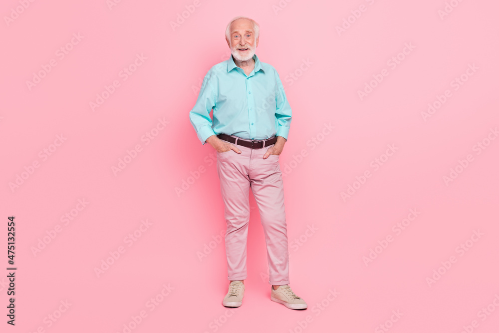 Full size photo of charming middle aged man put hands pockets trousers isolated pastel color background Full size photo of charming middle aged man put hands pockets trousers isolated pastel color background
