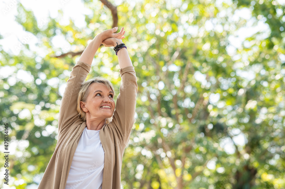 Portrait photo of happy senior Caucasian woman relaxing and breathing fresh air with sunlight in outdoors park. Elderly woman enjoying a day in the park on summer. Healthcare lifestyle and wellness Portrait photo of happy senior Caucasian woman relaxing and breathing fresh air with sunlight in outdoors park. Elderly woman enjoying a day in the park on summer. Healthcare lifestyle and wellness