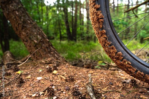 Black electric mountain bike front wheel full of sand in the forest