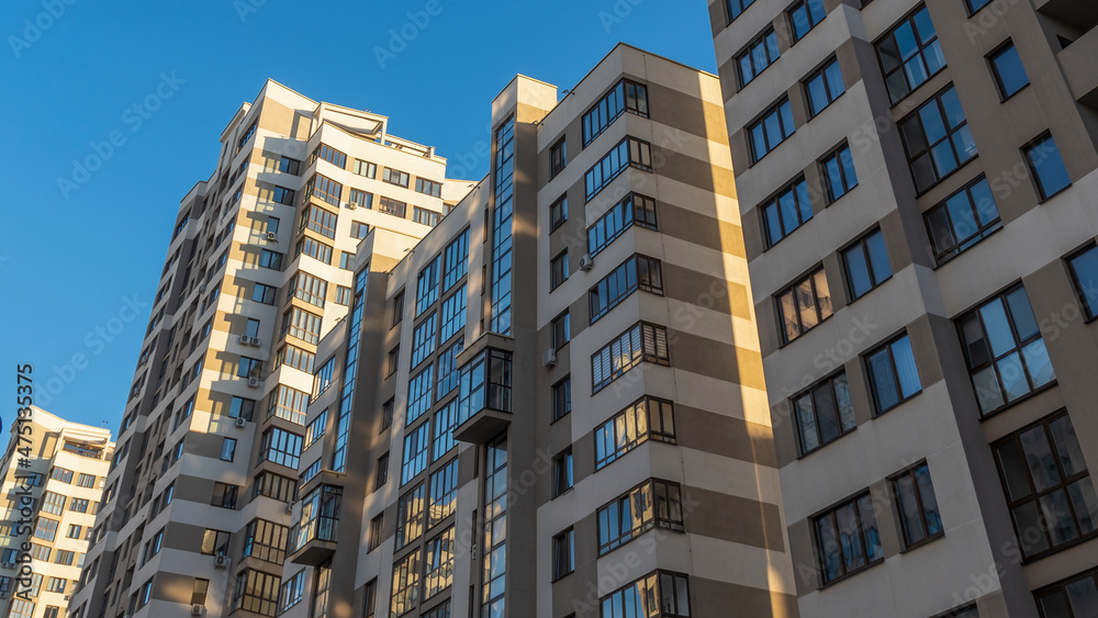 Cramped courtyard near high-rise buildings. A large apartment building in the background of a blue sky.
