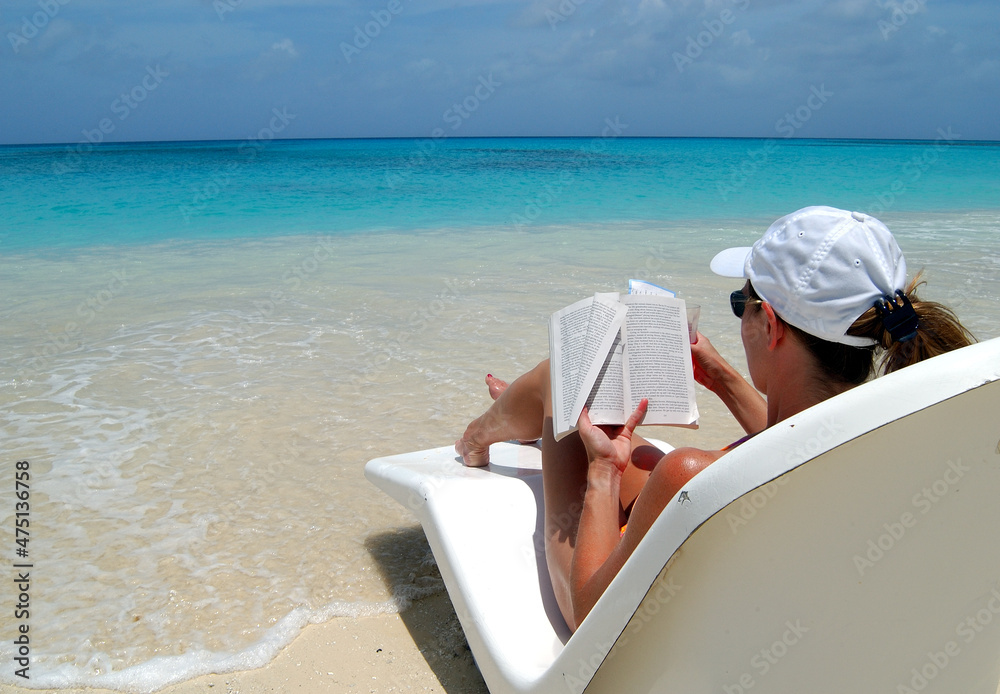 Woman reading book on tropical beach.