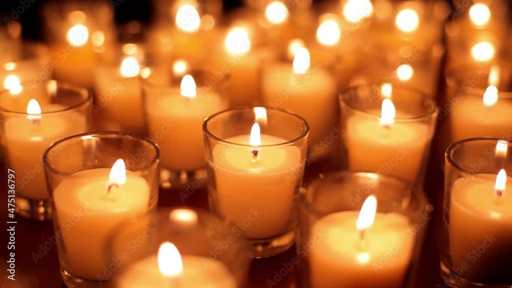 Camera moves past rows of glowing candles in a church or temple.