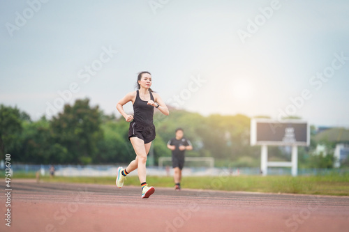 A mature Asian woman athlete runner jogging in city stadium in the sunny morning to keep fitness and healthy lifestyle. Active healthy runner jogging outdoor