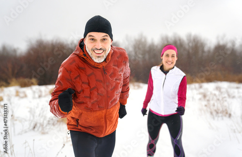 Runner couple jogging in park in warm winter sports clothing