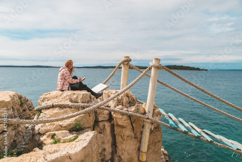 woman sitting at the edge drawing picture of seascape