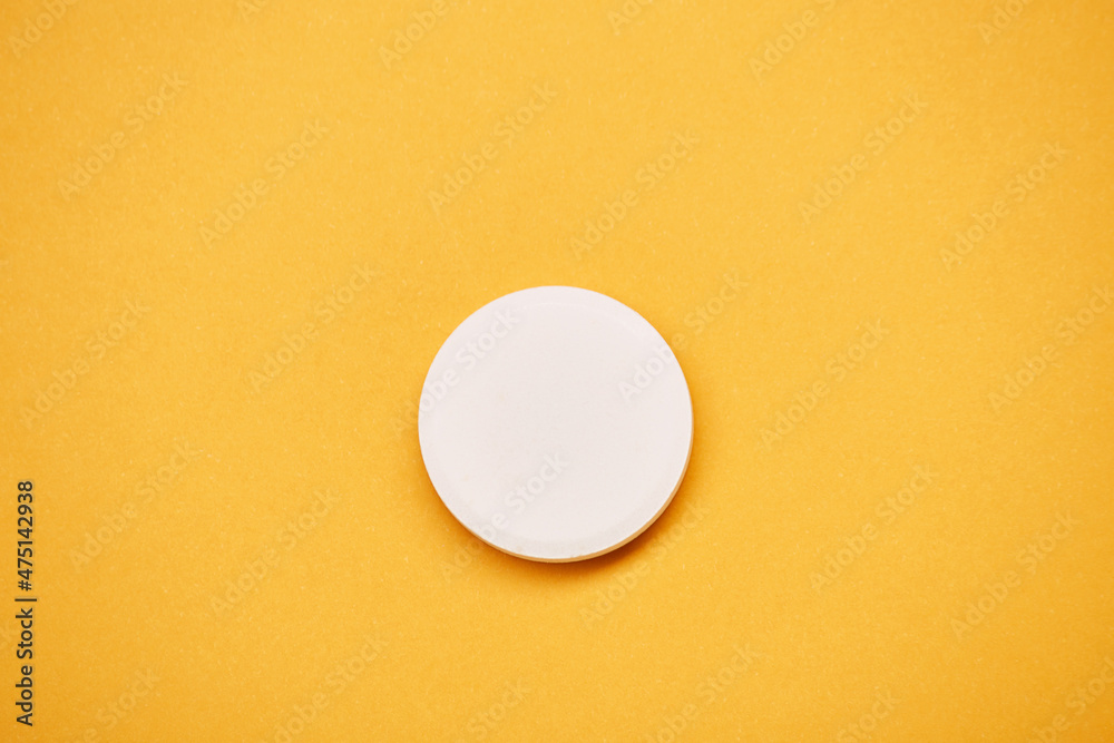 Pharmaceuticals medicament tablet round white pill medicine top view isolated on the bright solid yellow fond background