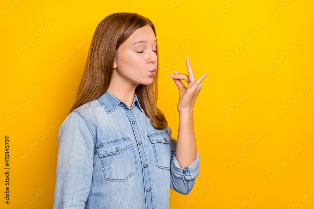 Photo of pretty teen blond girl try food wear jeans shirt isolated on yellow color background Photo of pretty teen blond girl try food wear jeans shirt isolated on yellow color background