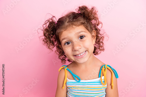 Portrait of attractive cheerful wavy-haired preteen girl looking at camera isolated over pink pastel color background