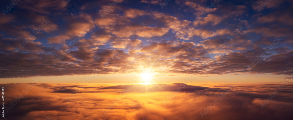 Wide panorama of setting sun above the clouds. Vibrant cloudscape of sun going under horizon