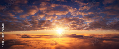 Wide panorama of setting sun above the clouds. Vibrant cloudscape of sun going under horizon © Vitalii