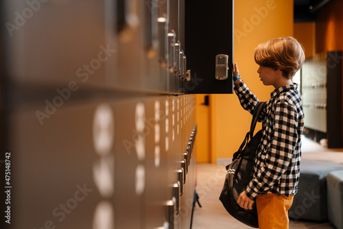White boy opening his cell in checkroom at school photo