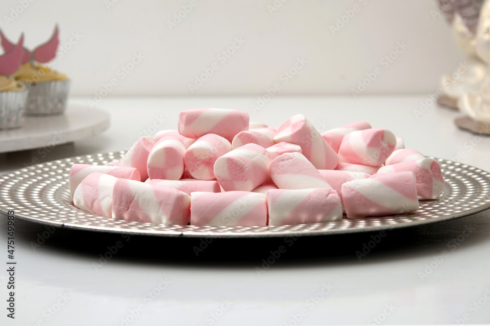 Plate full of mini white and pink marshmallows on a white background. Plate full of mini white and pink marshmallows on a white background.