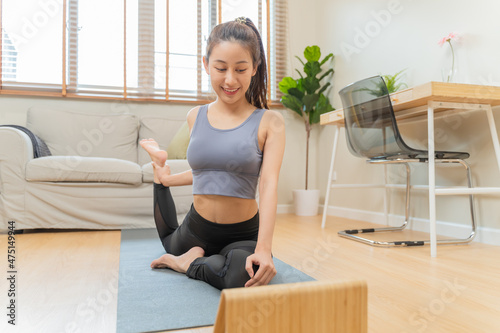 Fit, sporty asian young woman in sportswear sitting on floor, exercise on mat, watching online training videos on tablet in living room at home. Workout fitness, pilates for wellbeing, healthy care.