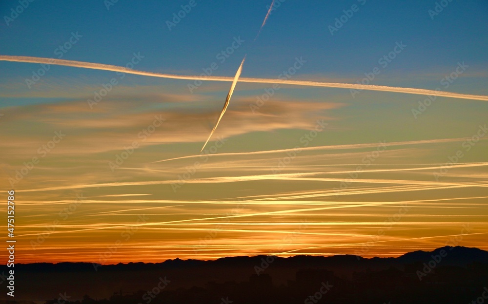 Dawn sky with aircraft vapour trails criss crossing showing busy aircraft activity in December 2021 over Northern Spain