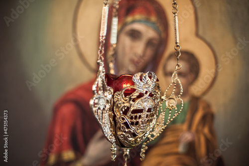 Hanging oil candle in church in front of religious iconography photo