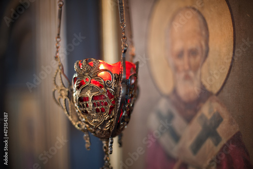 Hanging oil candle in church in front of religious iconography photo