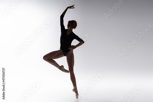silhouette of ballerina in bodysuit dancing on gray © LIGHTFIELD STUDIOS