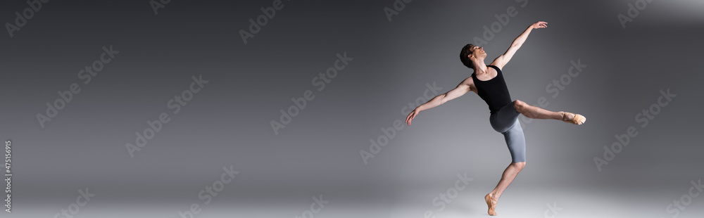 full length of elegant man performing ballet dance on dark grey, banner