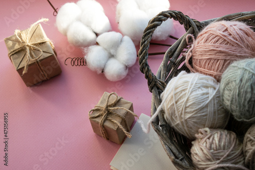 Basket with balls of thread. Gift boxes. Decorations for the holiday. Delicate colors  pink background.