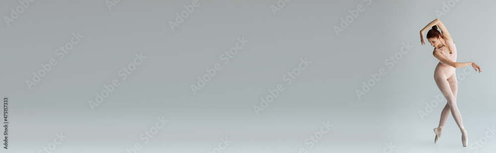 full length of young ballerina in pointe shoes and bodysuit on gray, banner full length of young ballerina in pointe shoes and bodysuit on gray, banner