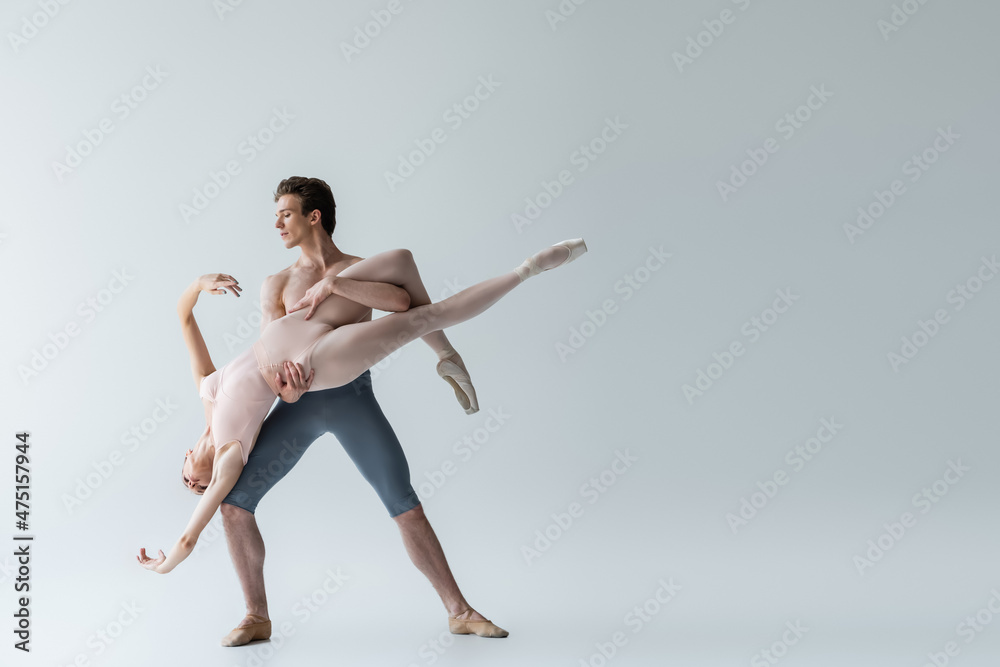full length of shirtless man and sensual ballerina performing ballet dance on grey full length of shirtless man and sensual ballerina performing ballet dance on grey