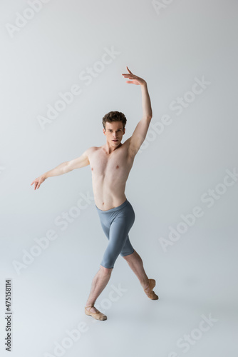 full length of elegant ballet dancer performing ballet dance isolated on grey