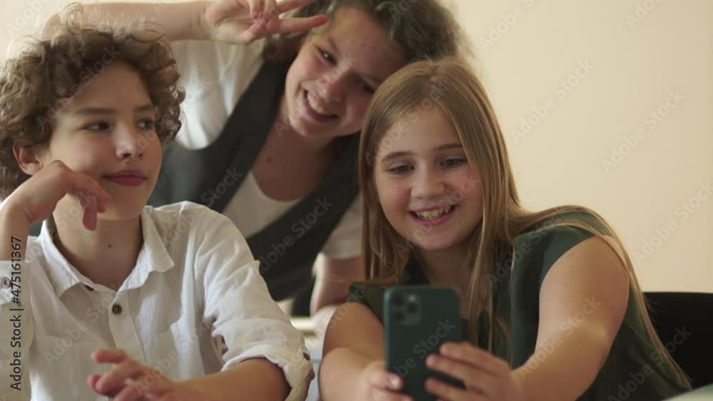Girl taking a selfie. Teenagers are photographed, a portrait of a boy and two girls at a desk with smartphone Girl taking a selfie. Teenagers are photographed, a portrait of a boy and two girls at a desk with smartphone