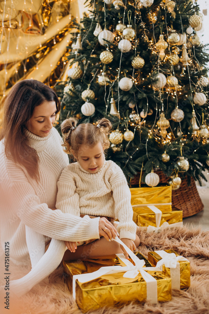 Mother with daughter holding christmas present under the christmas tree