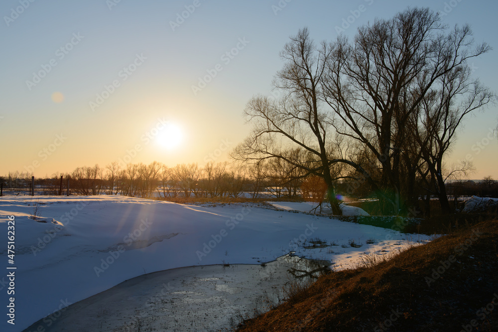 Spring evening landscape with a ravine with frozen water and snow drifts Spring evening landscape with a ravine with frozen water and snow drifts
