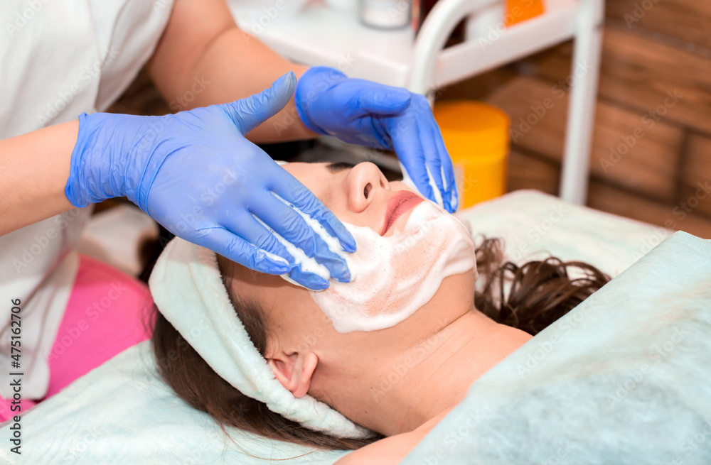 The girl at the beautician makes spa treatments, massage, facial cleansing and a mask for the skin. Cosmetic procedures in a beauty salon, facial skin care for rejuvenation.
