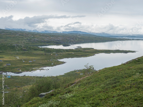 Lapland landscape at Virihaure lake with sami village Arasluokta houses, snow capped mountains and plain with shrubs. Sweden summer moody and foggy wild nature, Padjelantaleden hiking trail.