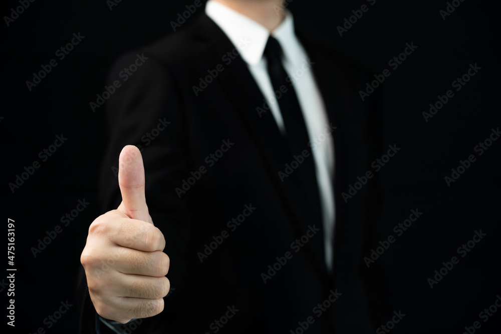 Unrecognizable smart businessman standing on the black background in photography studio and showing his thumb up.