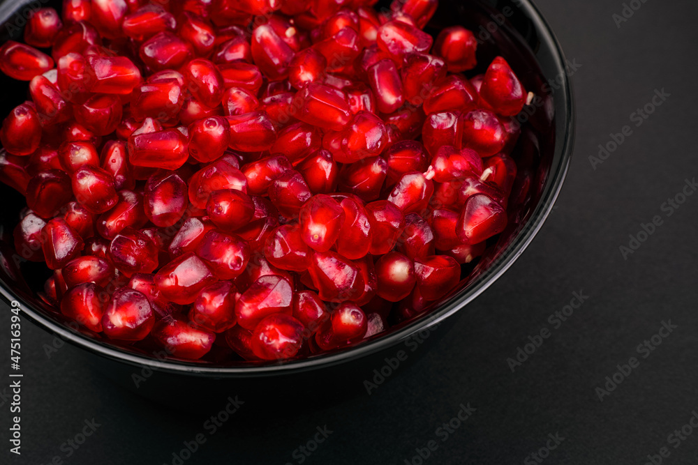 Ripe Pomegranate seeds in black bowl on black background Ripe Pomegranate seeds in black bowl on black background
