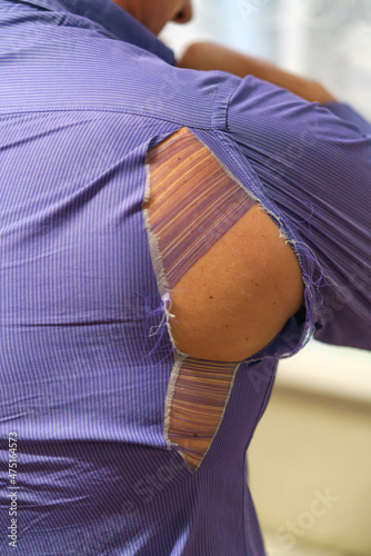 a hole on a purple man's shirt. Strong man rips purple shirt
