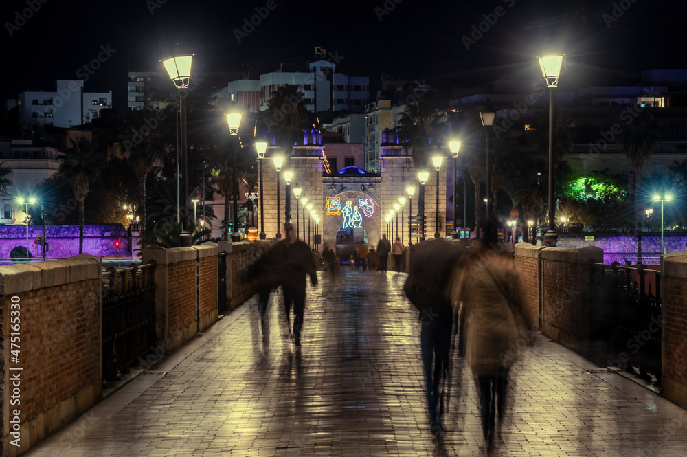 Obraz premium Puerta Palma, Badajoz illuminated with Christmas lighting, end of the year 2021, new year 2022 in Badajoz, people walking on the bridge