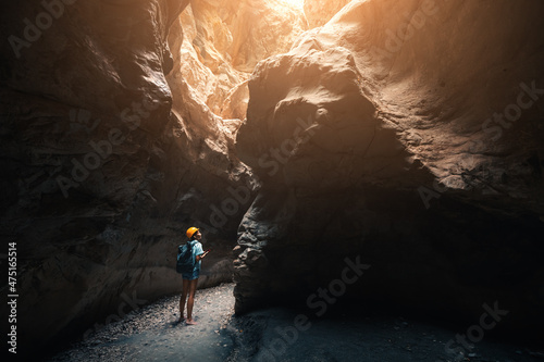 Person with helmet and backpack hiking in deep and dark but amazing canyon in mountains. New experience and outdoor leisure recreation
