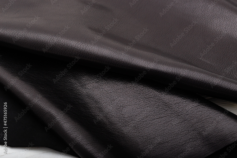 Fototapeta premium Dark brown chocolate glossy folded natural cow leather on the wooden table
