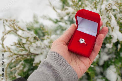 a ring with a large gemstone in a red box in the hand on a blurry background